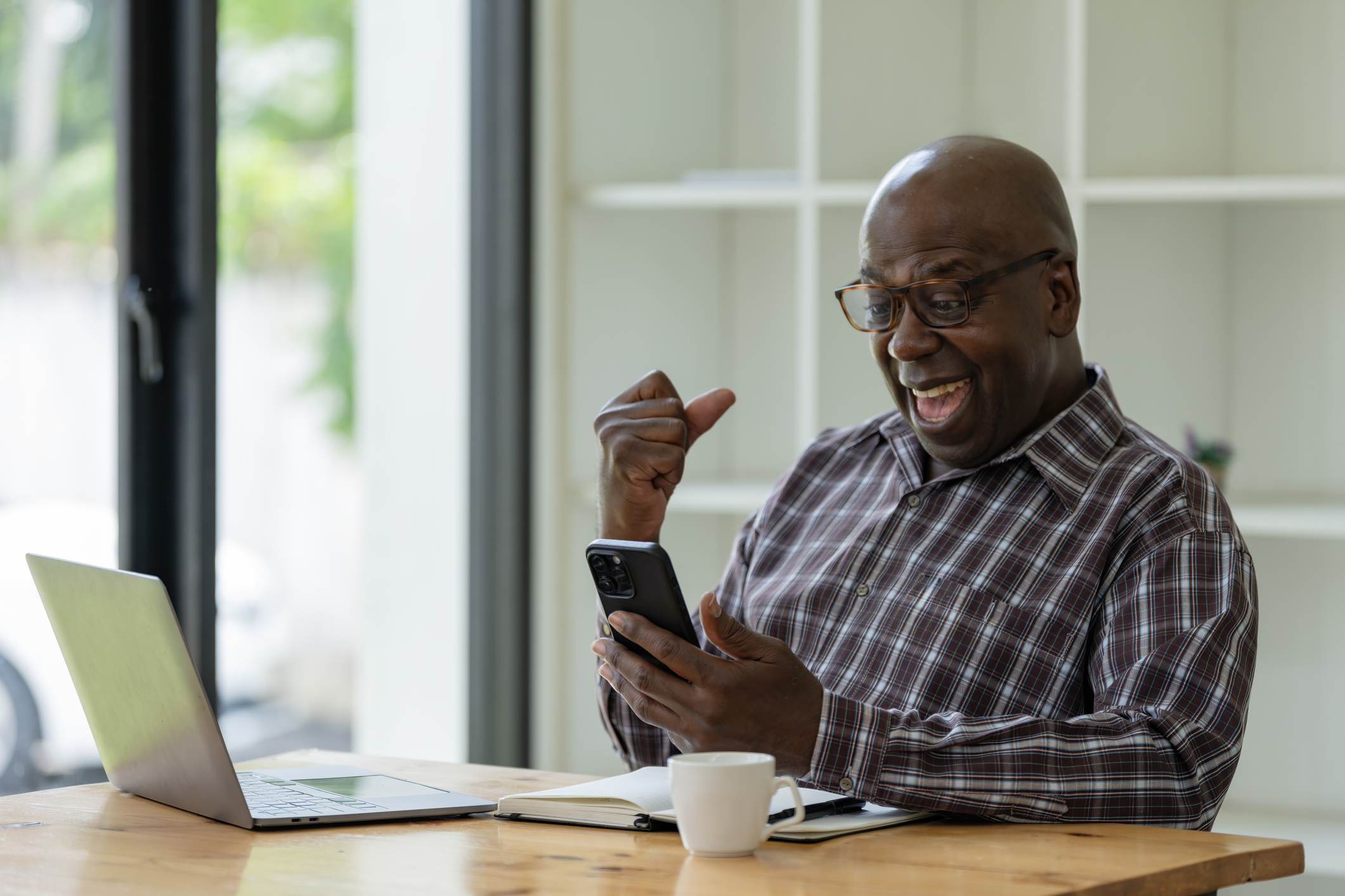 An upbeat individual reacting positively to financial updates on a smartphone.