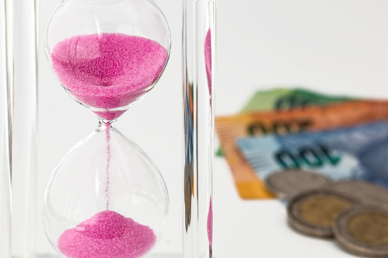 An hourglass filled with sand next to coins representing the 60-day rollover deadline.