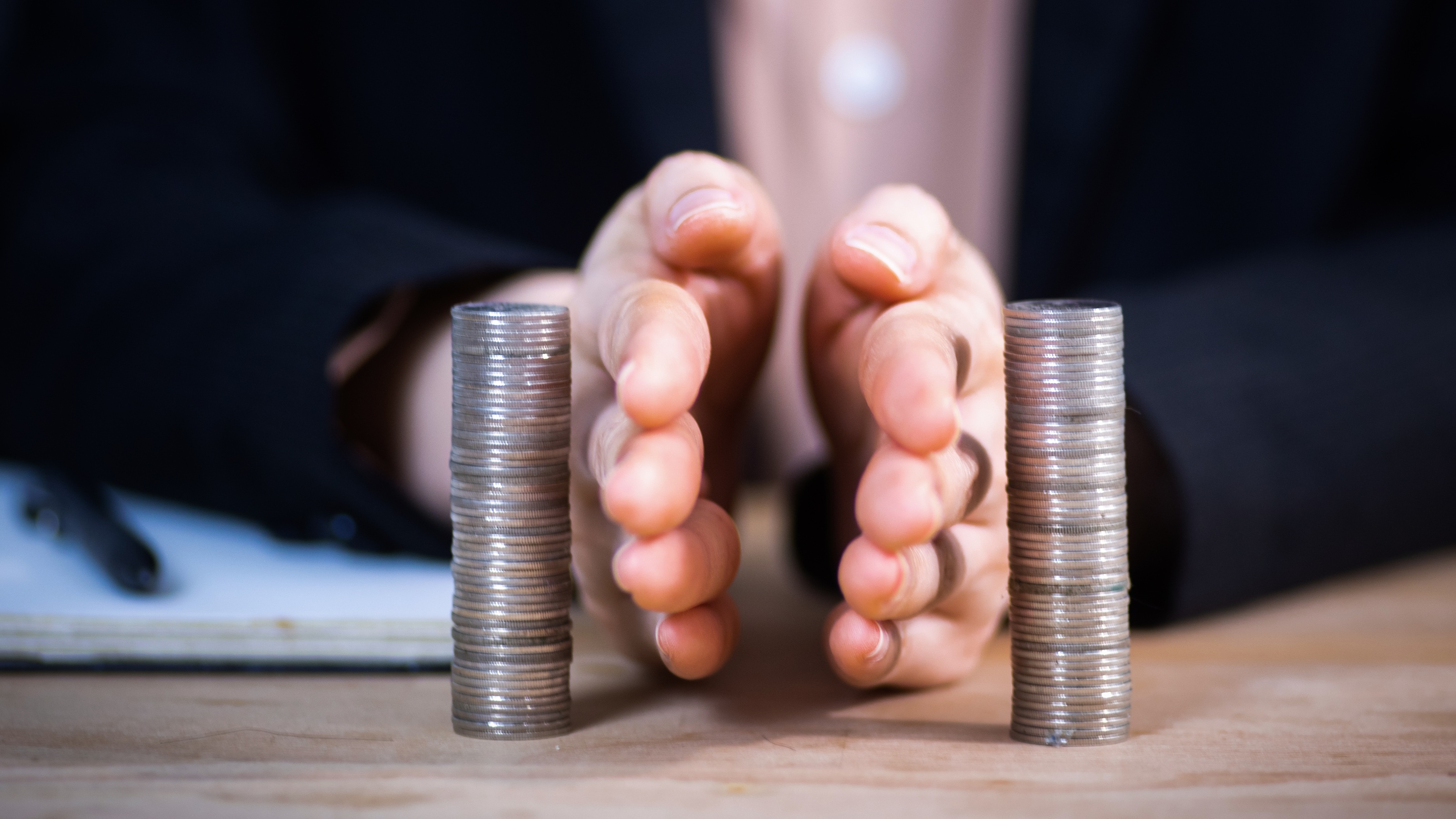 Two hands separating two vertical stacks of coins on a flat surface.