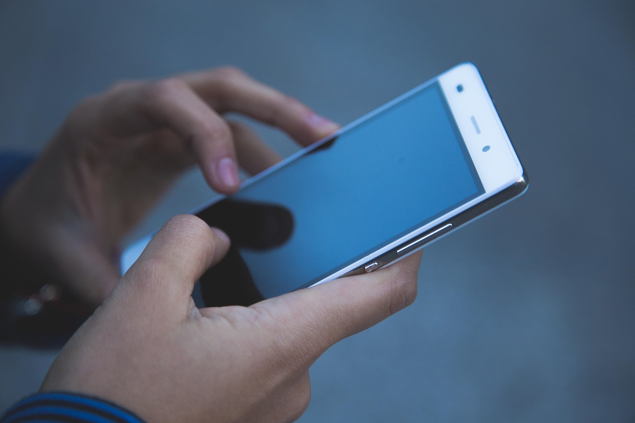 A person using a smartphone in a modern setting to manage mobile banking and benefits.