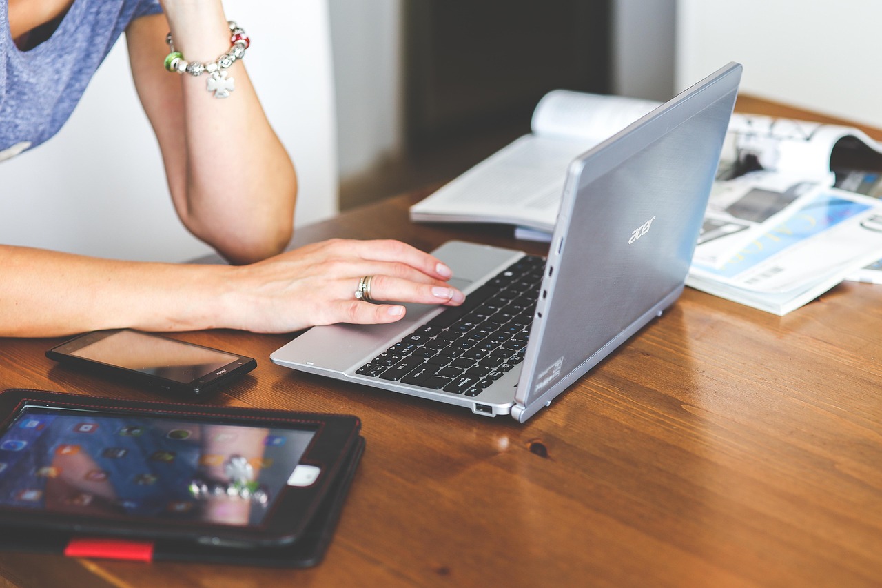 A person using a laptop and phone simultaneously to manage digital bank transfers.