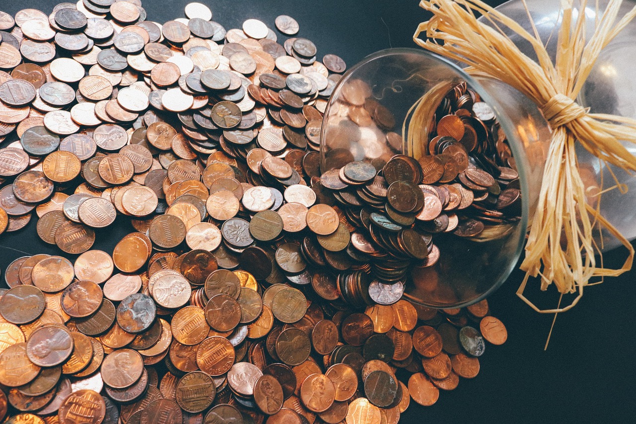 A glass jar filled with coins and small plants growing from the top.