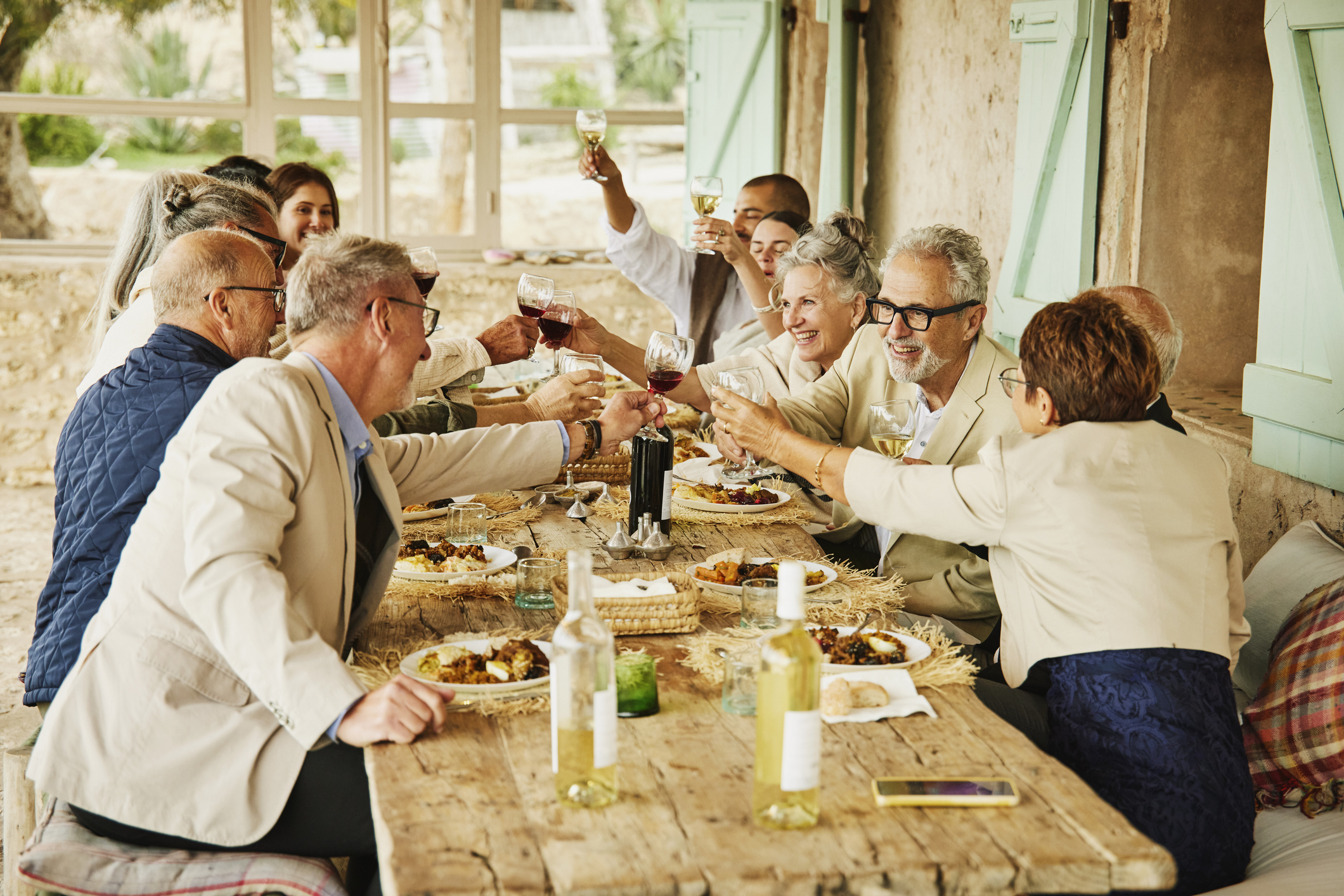 A group of friends laughing and enjoying a formal dinner at a winery with glasses of wine.