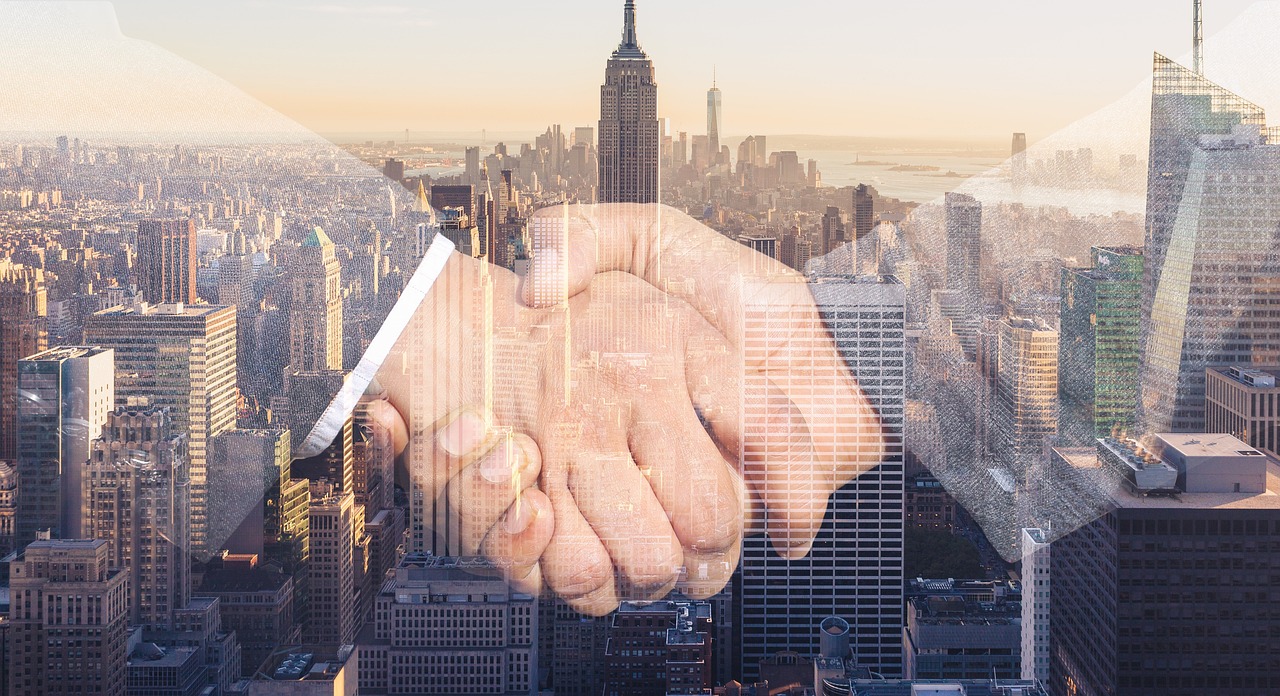 Two people shaking hands across a desk after reaching a financial settlement.
