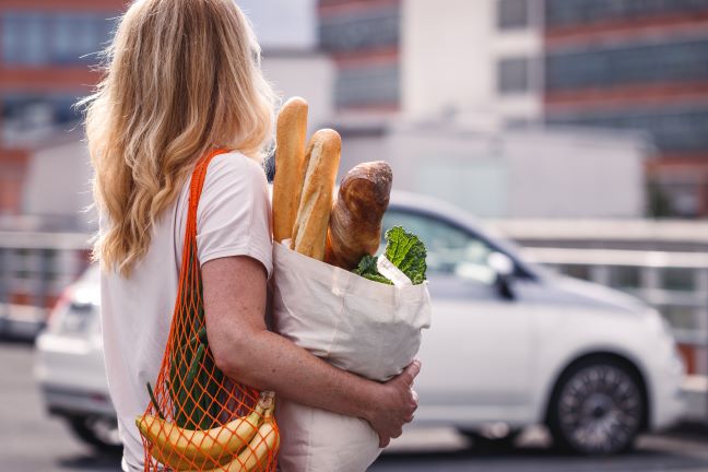 Woman carrying groceries in reusable bags during a shopping trip.