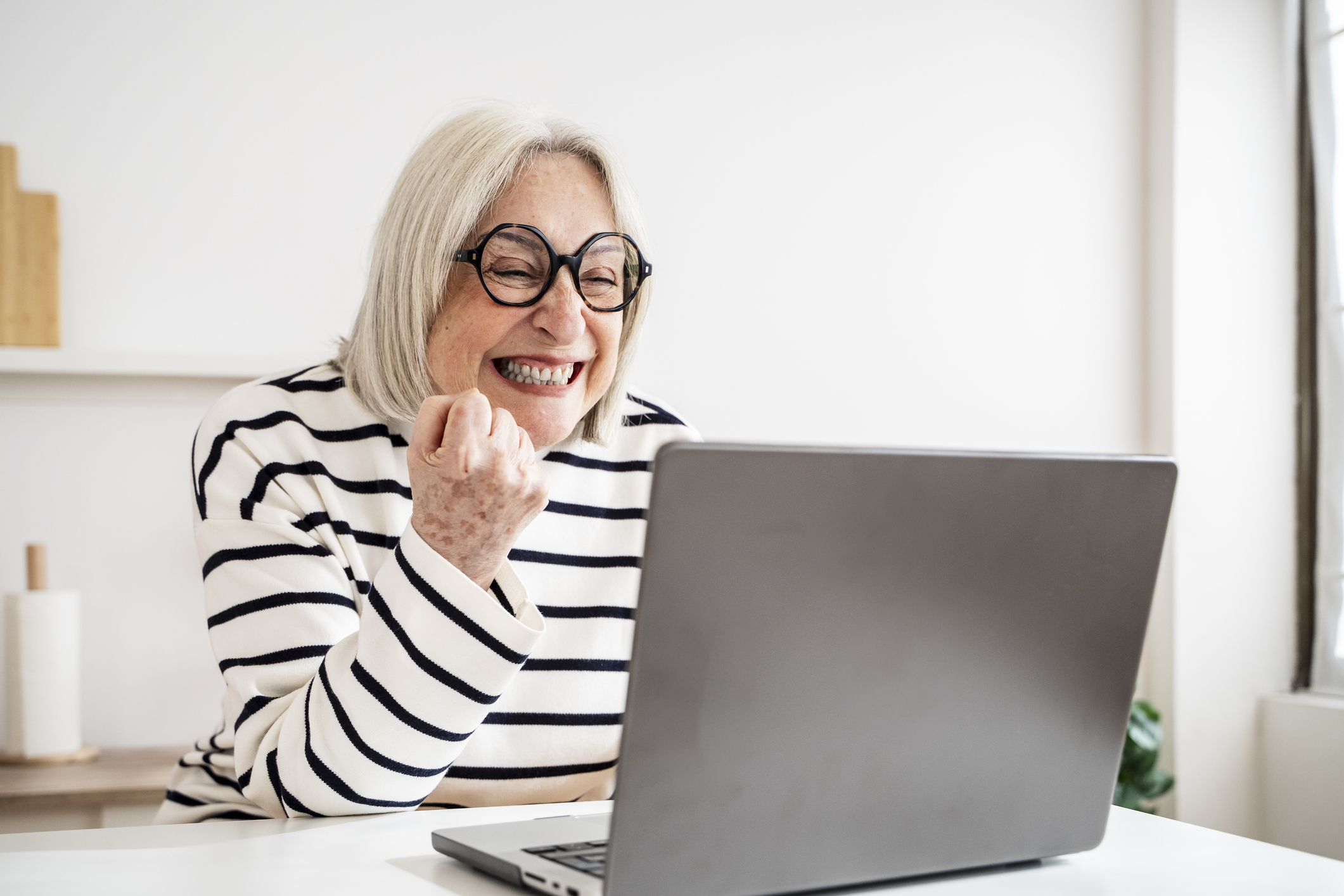A woman expressing joy and excitement while looking at financial growth on her computer screen