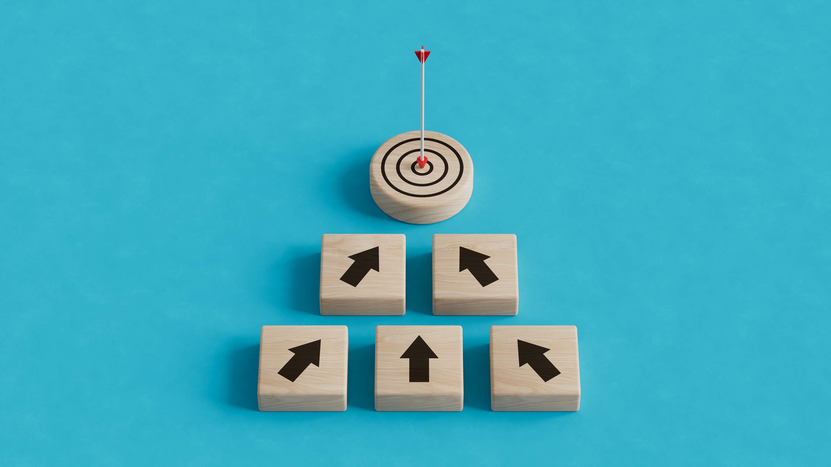 An arrow in the center of a target atop a pyramid of wooden blocks with up arrows.