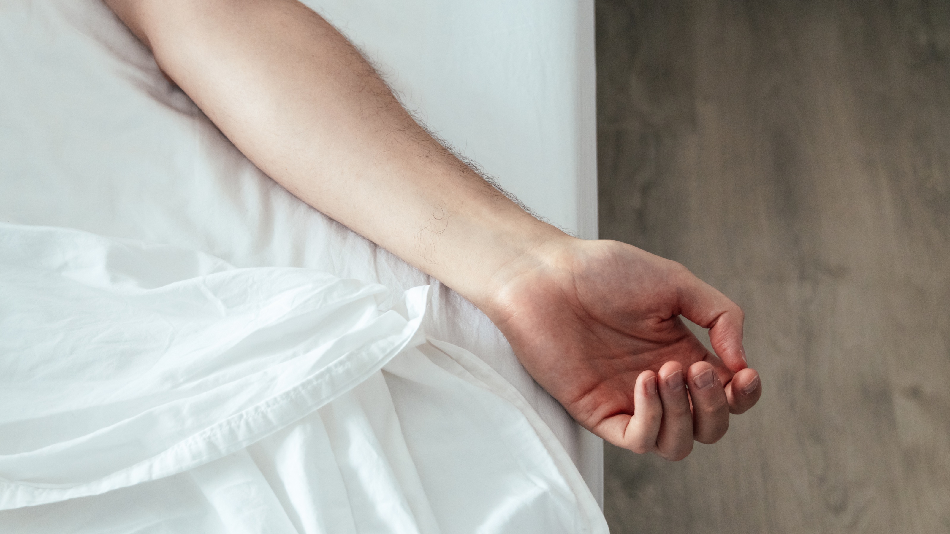 A person sleeping peacefully in white bedsheets.