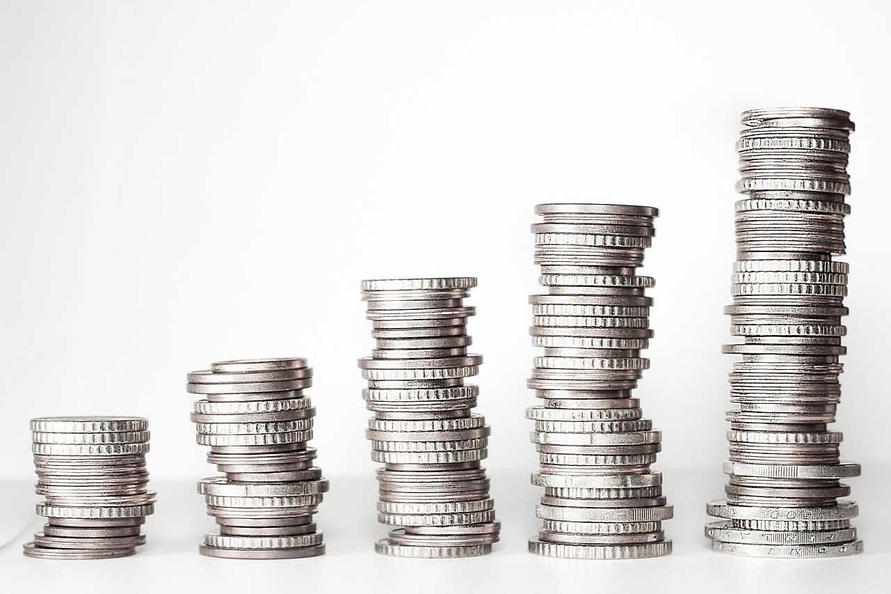 Stacks of coins next to a compass, representing financial direction and account types.