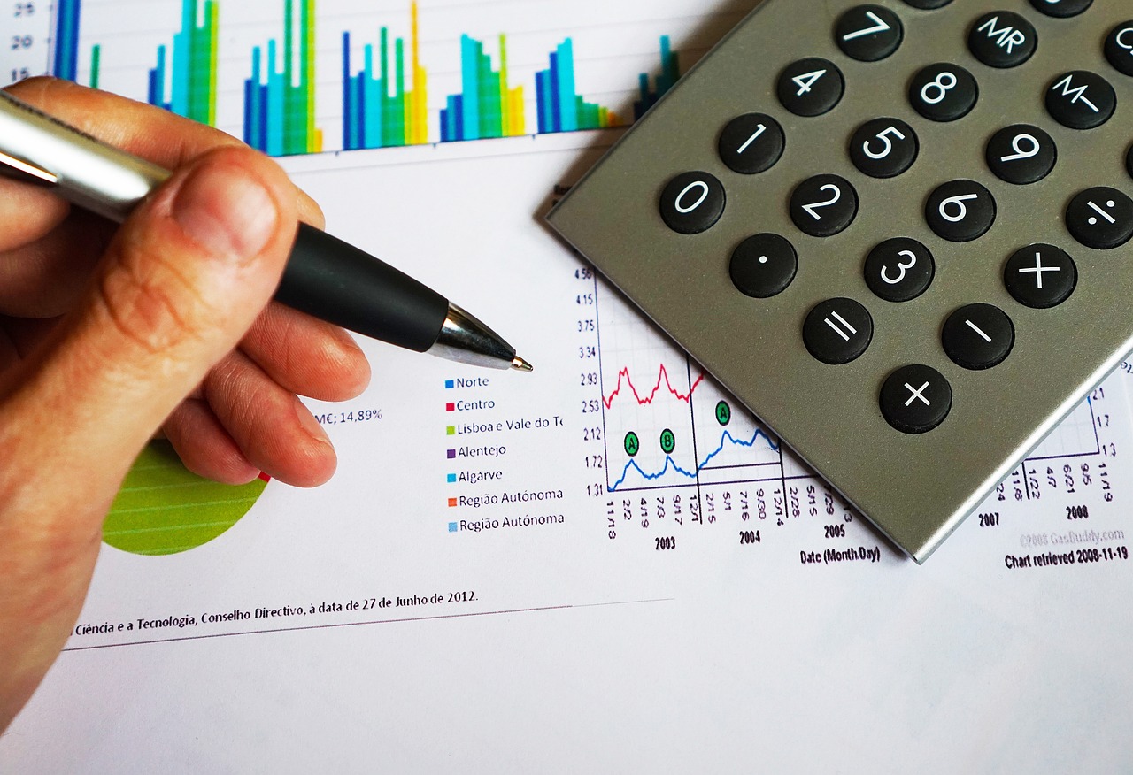 A modern calculator and pen on a white desk with financial documents.