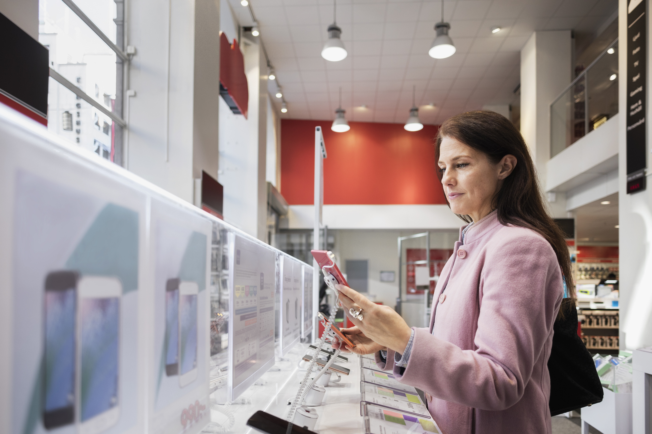 A person looking at their smartphone while standing in a retail environment.
