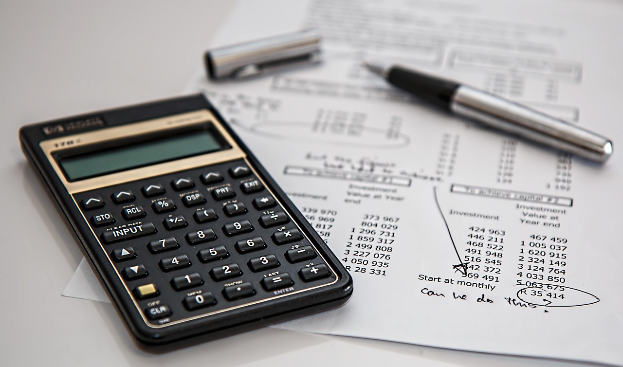 A silver calculator sitting on top of financial spreadsheets and tax documents.