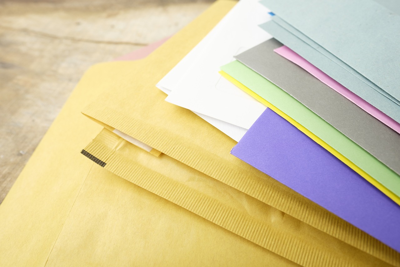 A hand holding a formal business envelope with a certified mail receipt attached.