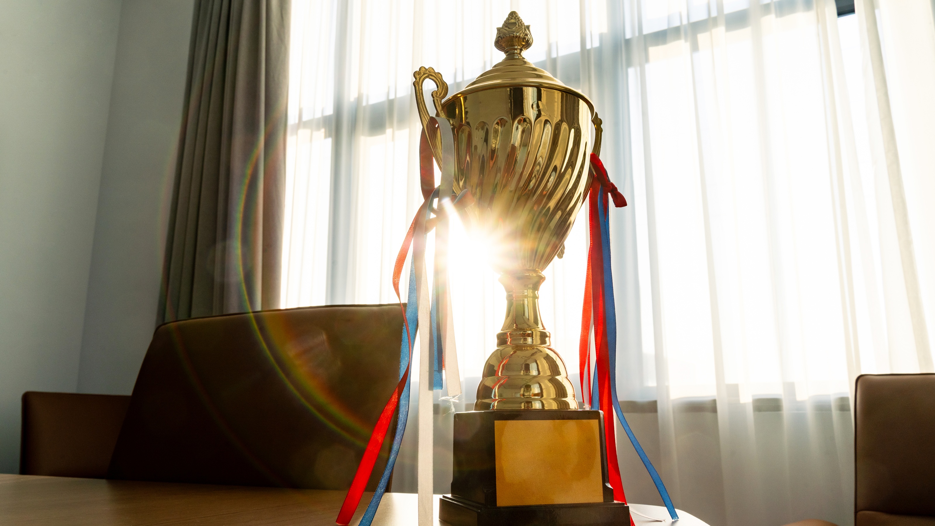 A gold trophy on a table illuminated by sunlight.