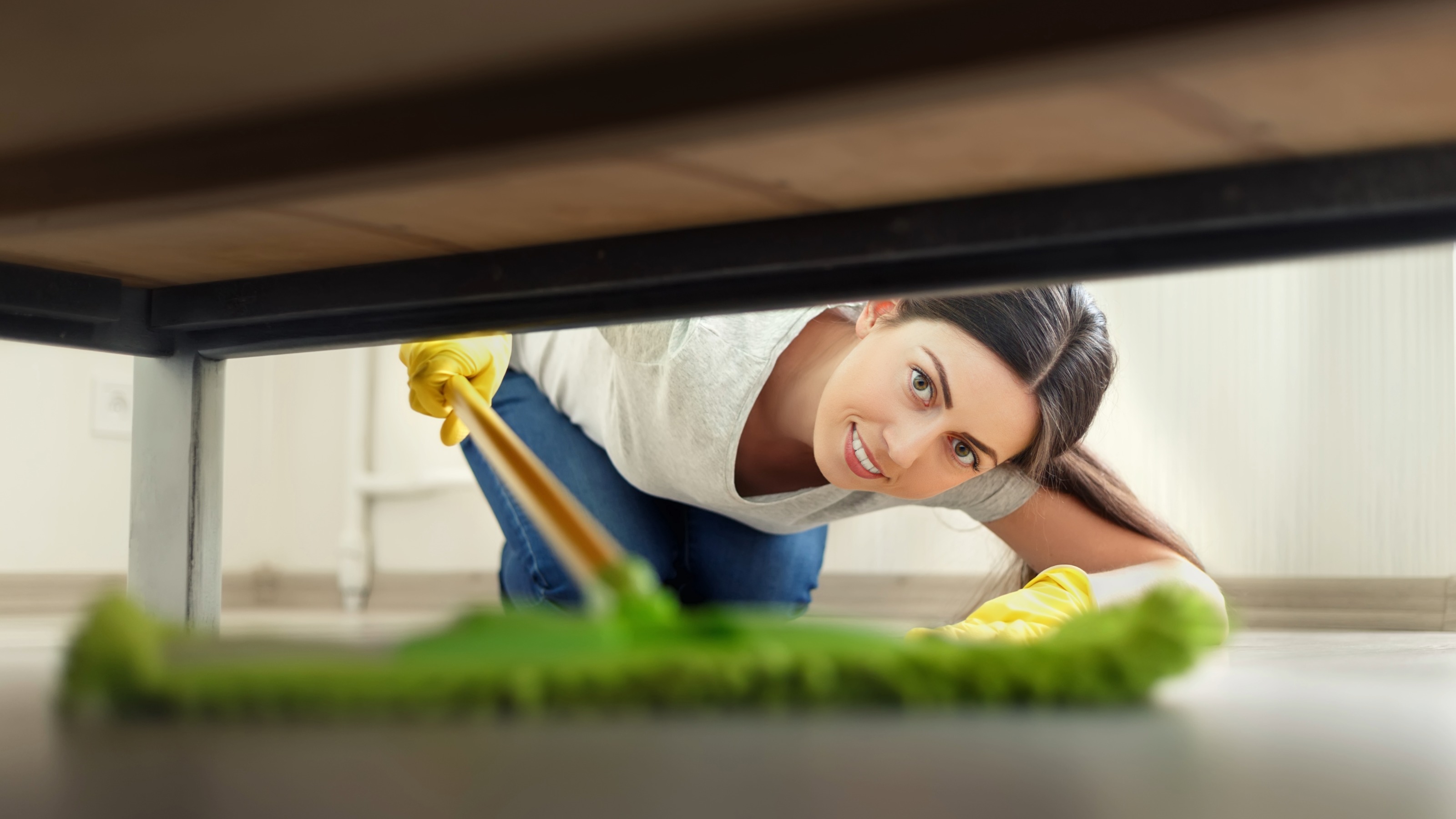 A person cleaning under a bed, representing the search for hidden financial leaks.