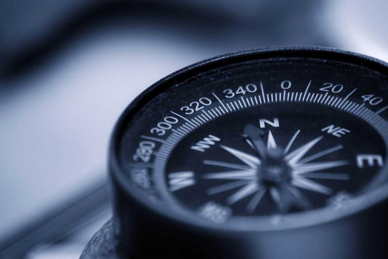 A modern compass sitting on a topographical map symbolizing a clear path forward.