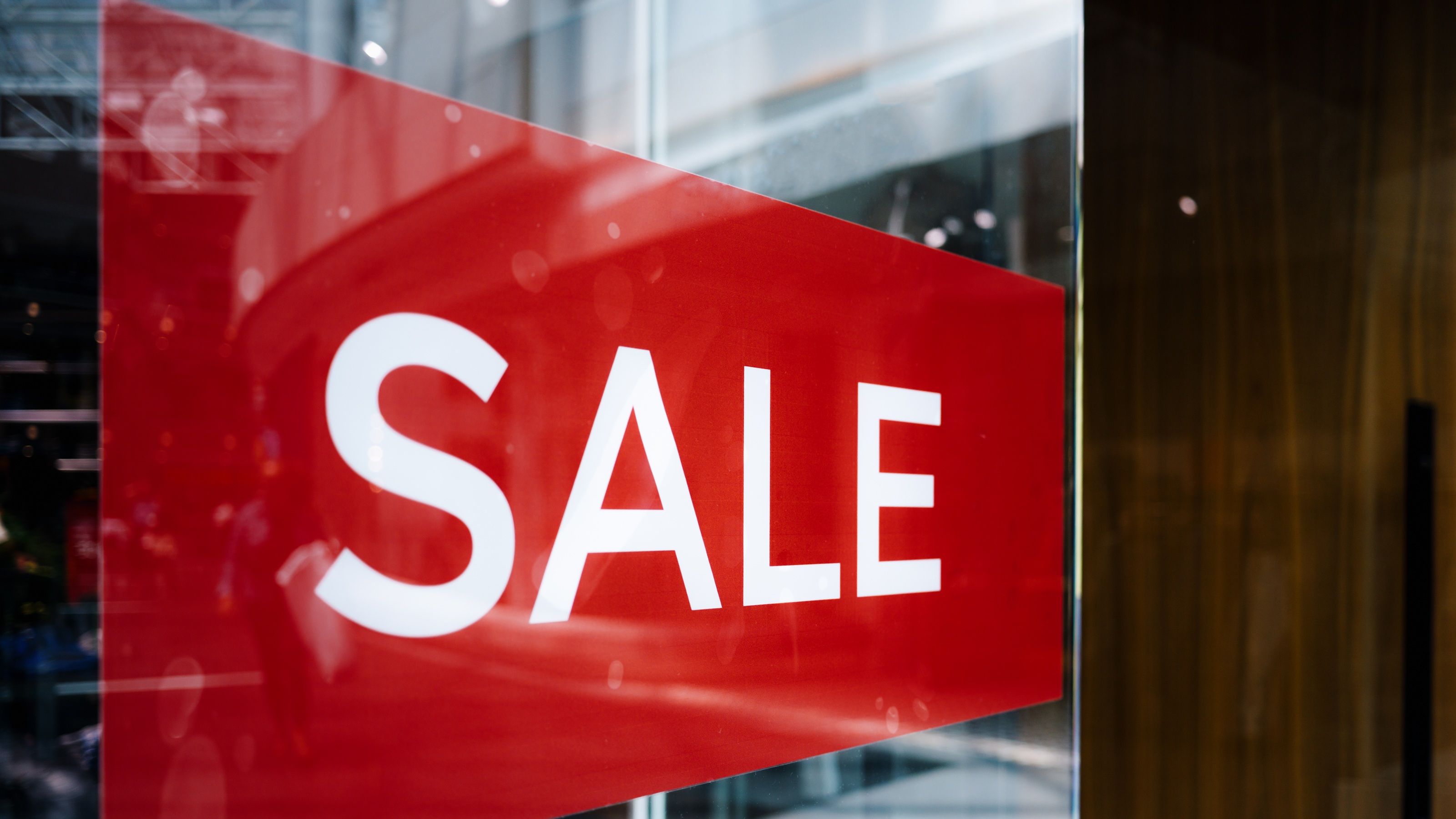 A large red 'SALE' sign reflecting in a store window.