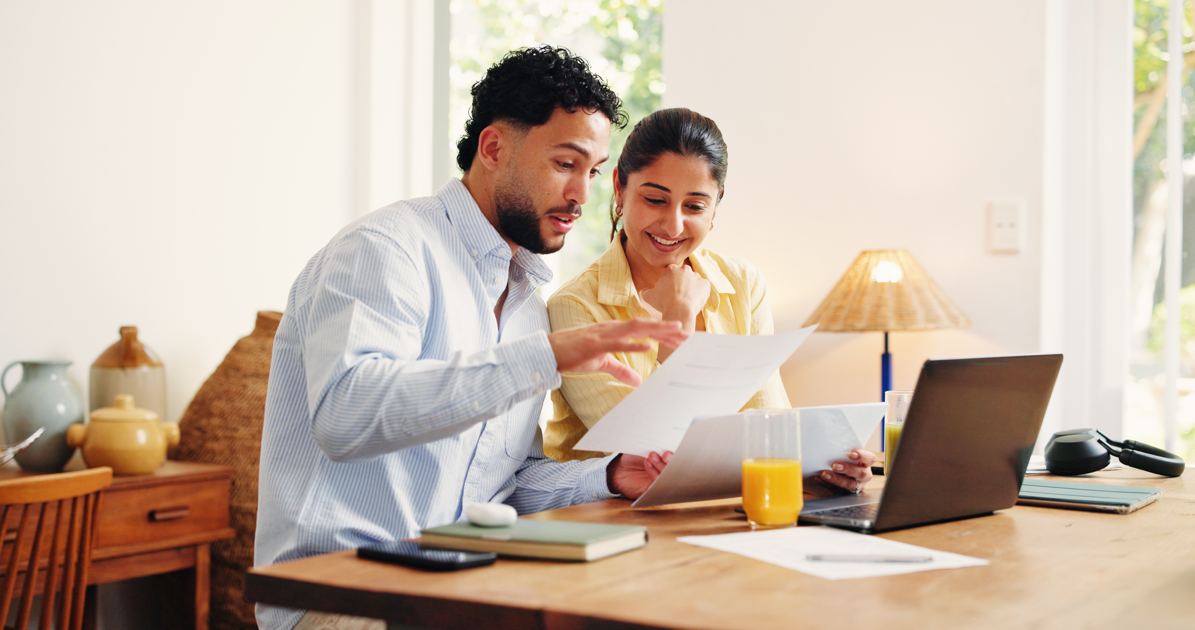 A couple focused on their personal finance spreadsheet on a laptop at home.