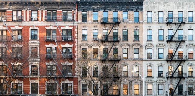 Dense urban apartment blocks in New York City under a clear sky.